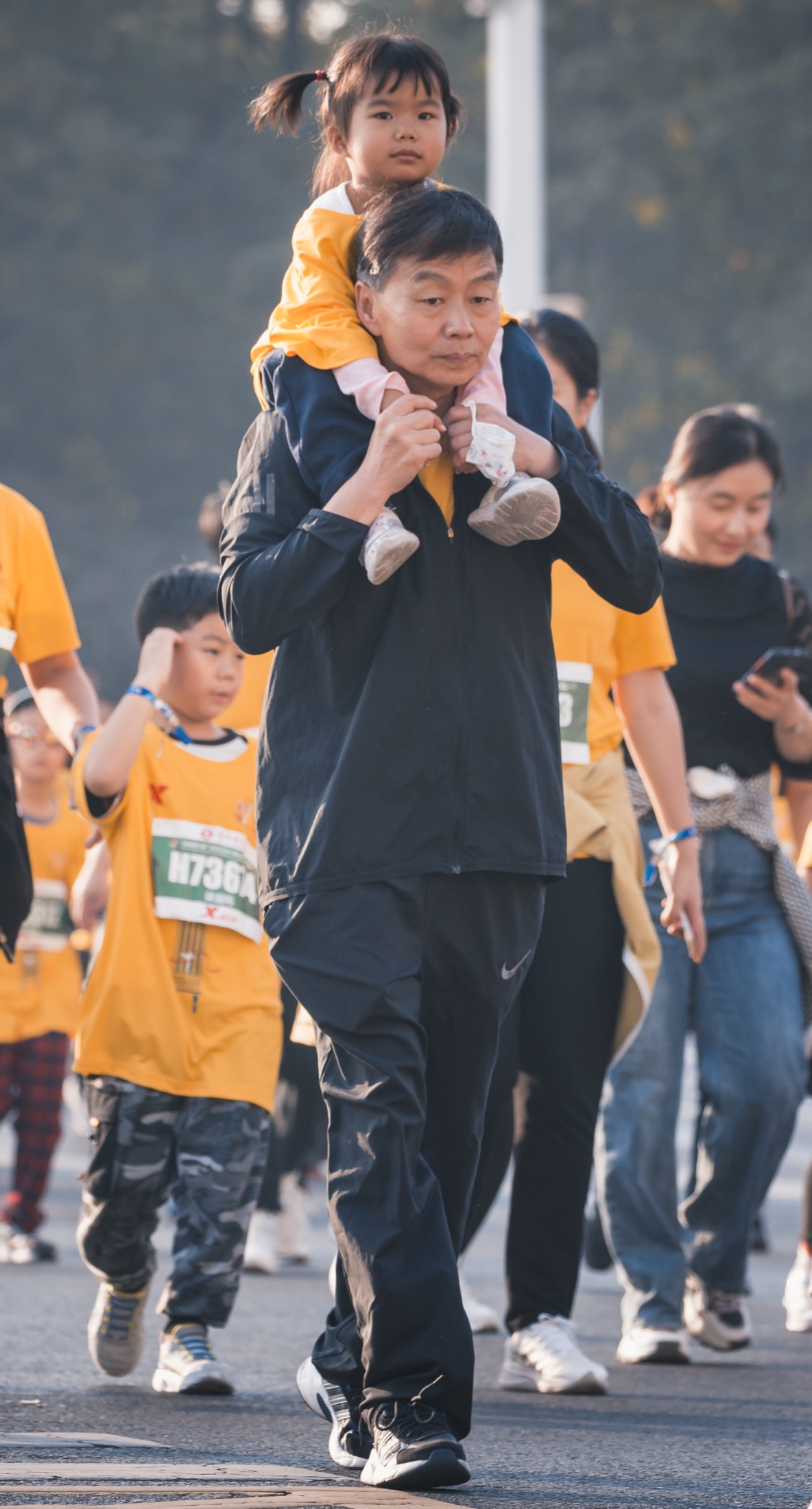 郑州马拉松现场，一位父亲肩扛孩子向前行进